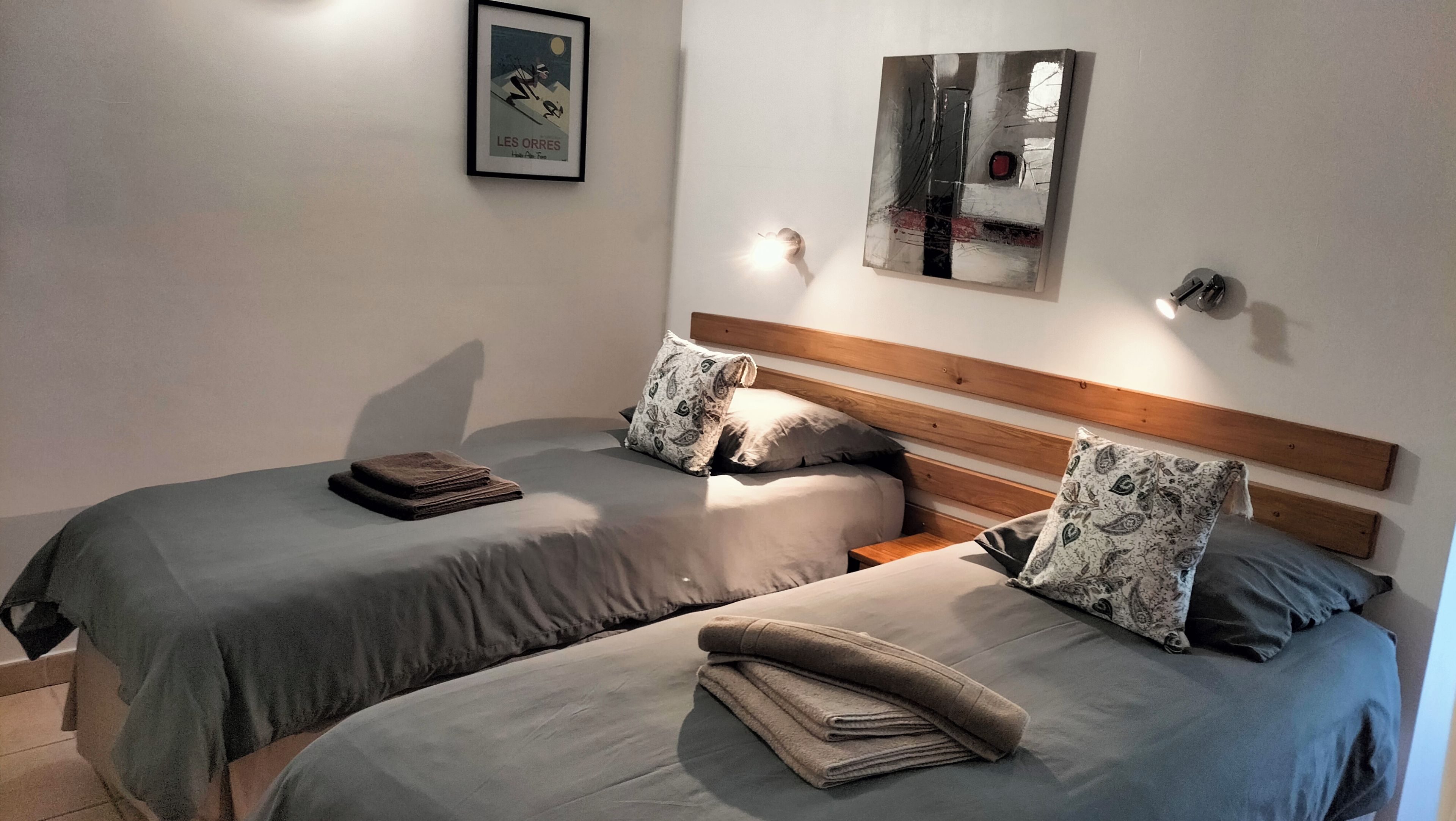 Un lit double avec une tête de lit en bois, deux oreillers et une serviette pliée.