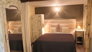 Ein Doppelbett mit dunkler Bettdecke, einem Holzkopfstück und zwei Nachttischlampen.