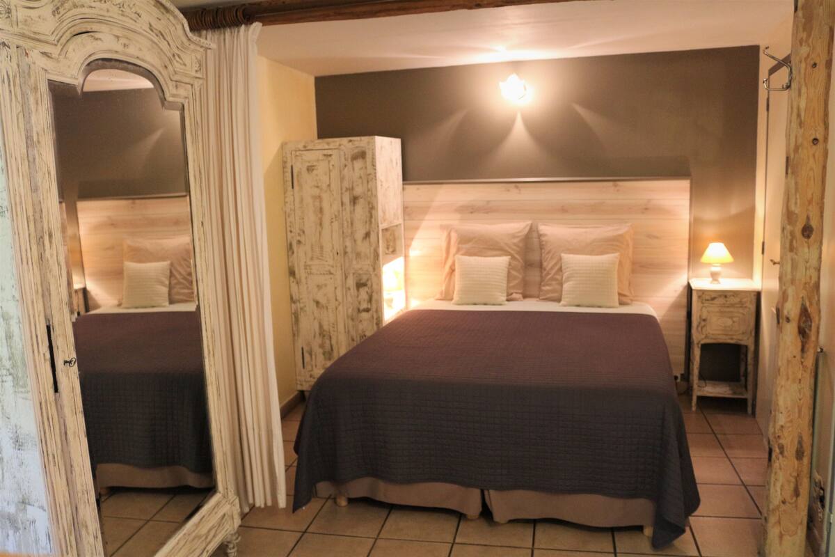 A double bed with a dark bedspread, a wooden headboard, and two bedside lamps.