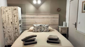 Un dormitorio con cabecera de madera, una cama con dos almohadas, una mesita de noche y un armario.