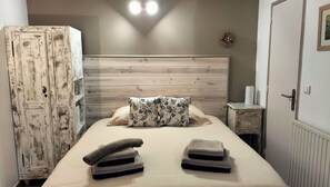 Ein Schlafzimmer mit hölzernem Kopfteil, einem Bett mit zwei Kissen, einem Nachttisch und einem Kleiderschrank.
