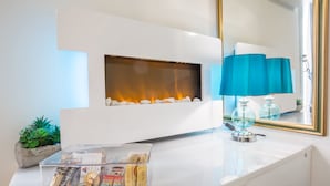 A modern bathroom with a white vanity, a glass container with toiletries, a blue lamp, and a mirror with a gold frame.