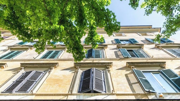 A multi-story building with a classical architectural style, featuring evenly spaced windows with shutters and a central entrance.