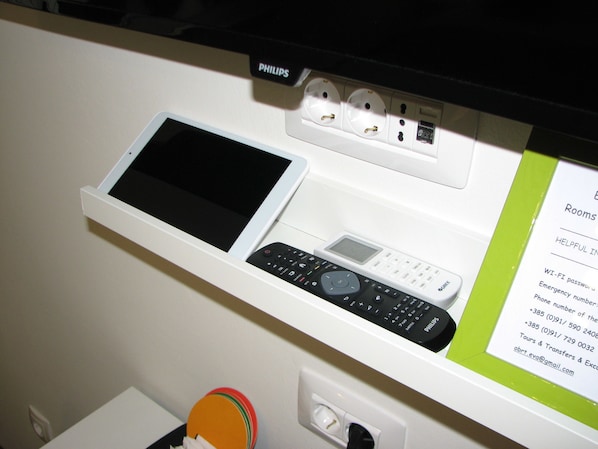 A white shelf with a tablet, a remote control, and a power strip with a Philips brand outlet. - Eva Luxury Rooms & Apartments (Plitvicka Jezera)