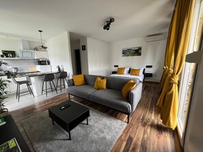 A modern living room with a grey sofa, yellow cushions, a black coffee table, and a kitchen area in the background. - Eva Luxury Rooms & Apartments (Plitvicka Jezera)