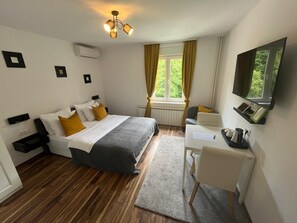 A hotel room with a bed, a desk, a chair, a television, and a window with curtains. - Eva Luxury Rooms & Apartments (Plitvicka Jezera)