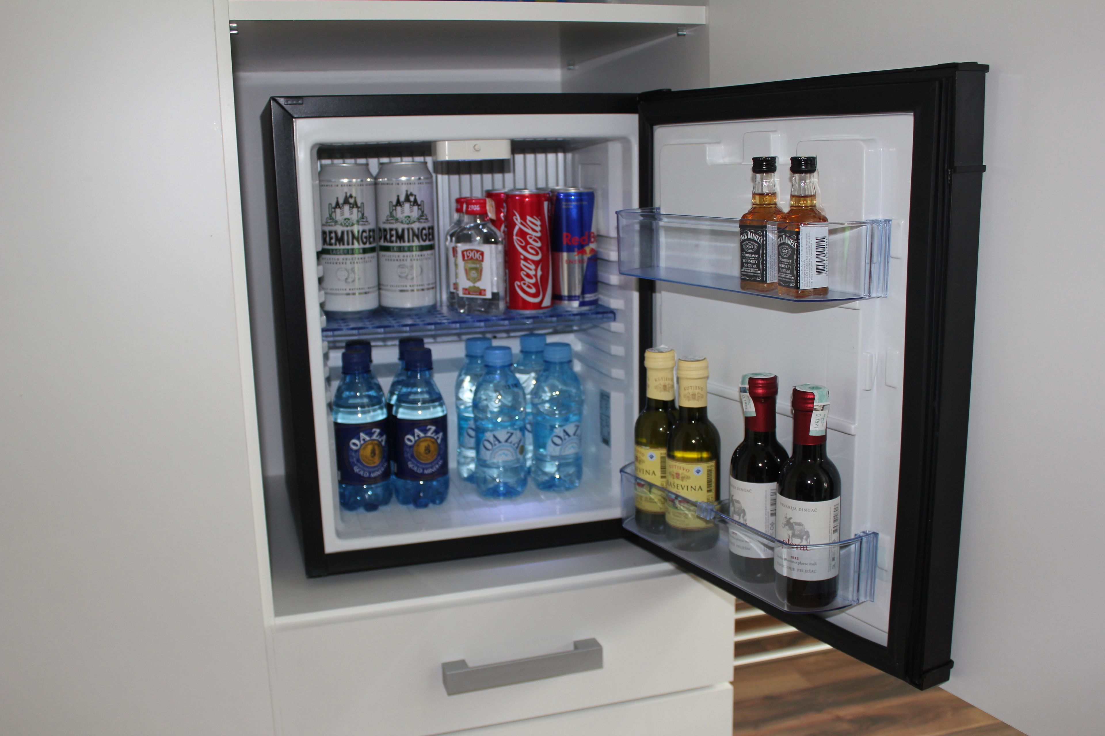 Un refrigerador lleno de bebidas, incluyendo cerveza, refrescos y vino.