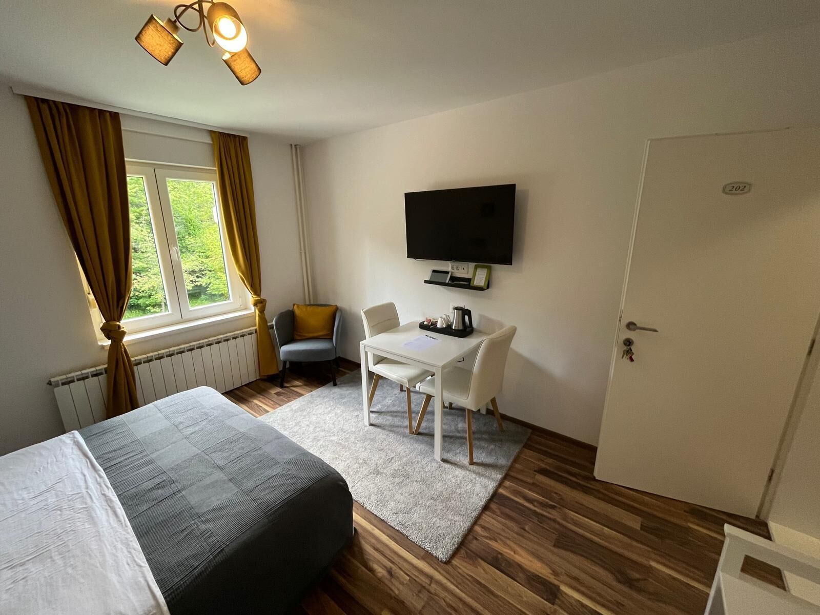 Una habitación de hotel con cama, escritorio con silla, televisor y puerta.