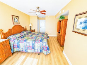 A bedroom with a bed, a ceiling fan, a dresser, and a door. - Crescent Shores S 506 (North Myrtle Beach)
