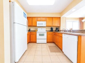 A kitchen with wooden cabinets, a white refrigerator, a microwave, a stove, and a dishwasher. - Crescent Shores S 506 (North Myrtle Beach)