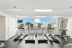Een sportschool met loopbanden, een hometrainer en krachtapparaten.