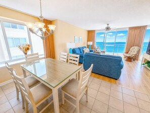 Een moderne woonkamer met een glazen eettafel, een blauwe bank en uitzicht op de oceaan.