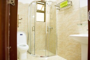 A bathroom with a glass-enclosed shower, a toilet, and a sink. - Exquisite Serviced Apartment (Nairobi)