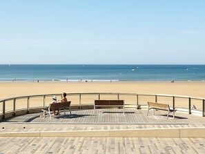 Een strandboulevard met bankjes en een hekwerk.