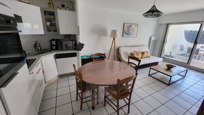 A compact living space with a kitchen, dining area, and a sofa with a view. - Cozy 1BR Apartment with Terrace, 200m from Sandy Beach (Les Sables-d'Olonne)