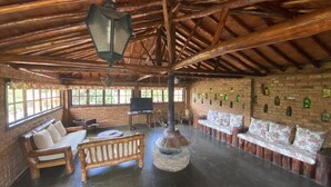 Un intérieur rustique avec un plafond en bois, des murs en briques, une cheminée et un téléviseur.