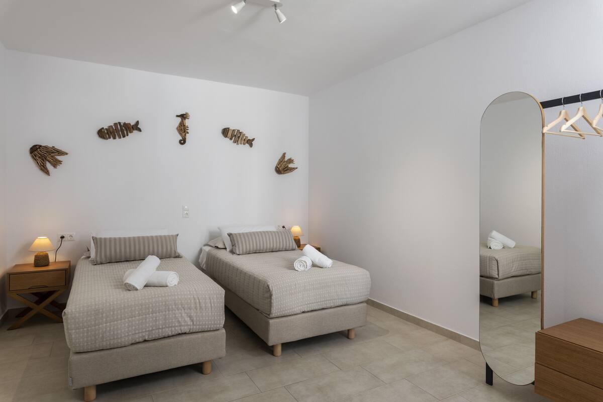 A modern bedroom with two beds, a large mirror, and wall-mounted fish decorations.