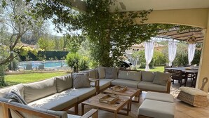 Une terrasse extérieure avec un canapé modulable, une table basse en bois et des chaises en osier.