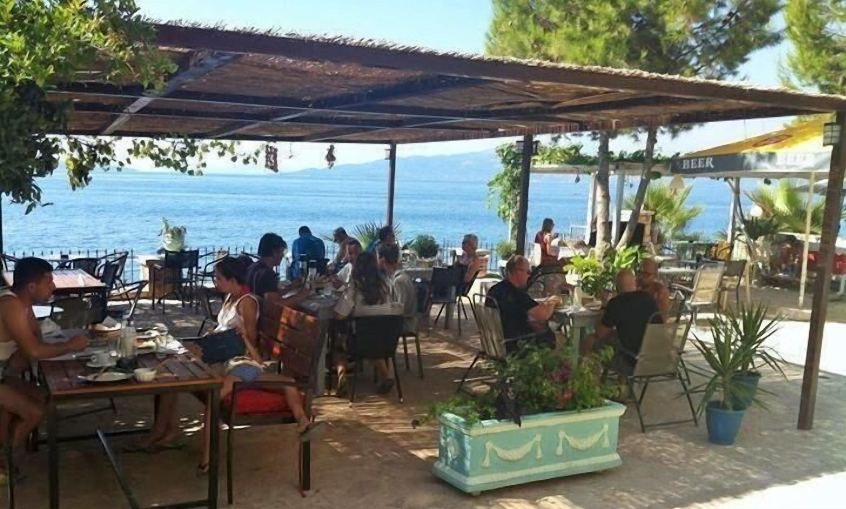 Ein Straßencafé mit Tischen und Stühlen mit Blick auf ein Gewässer.