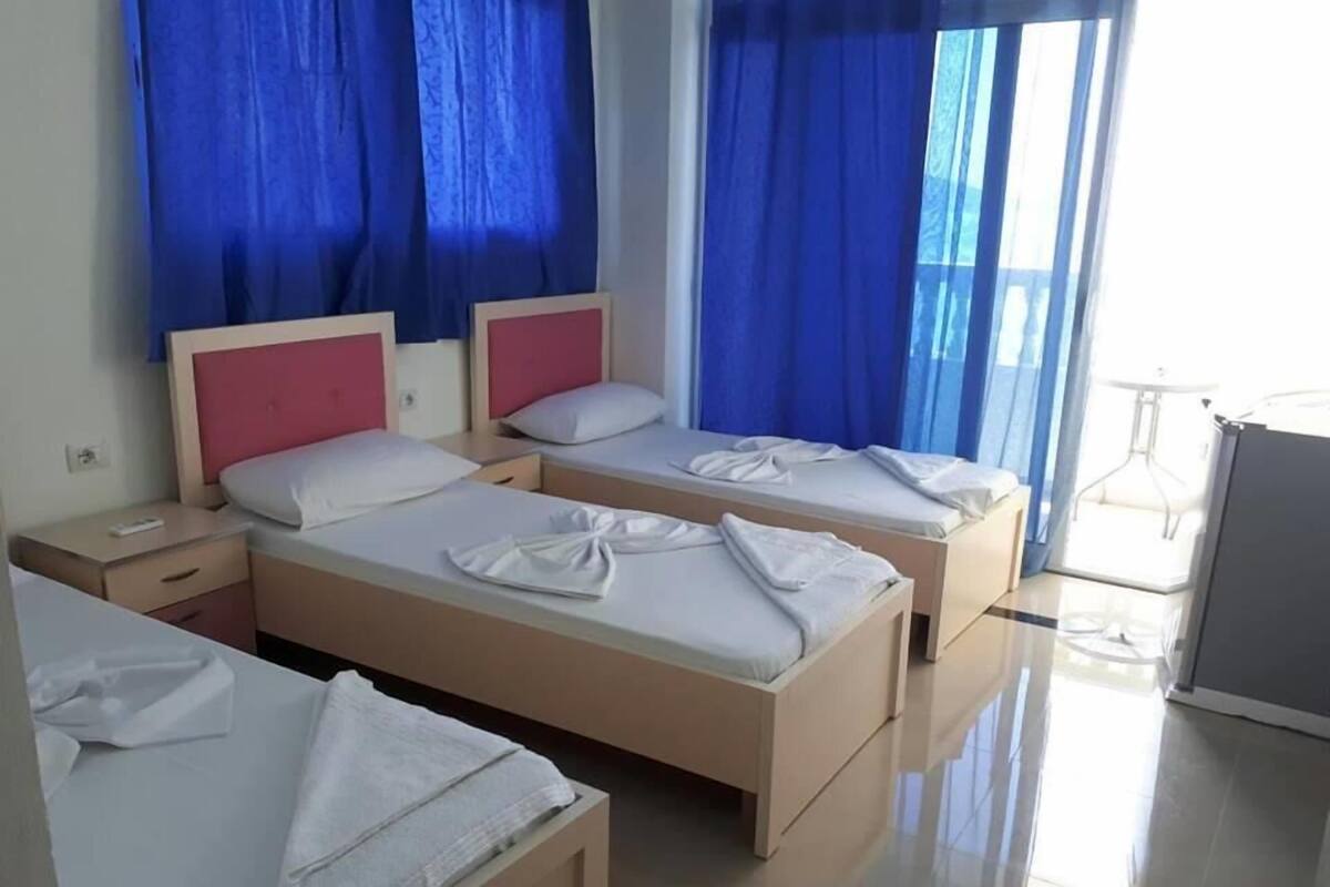 A hotel room with two beds, a small table, and a chair.
