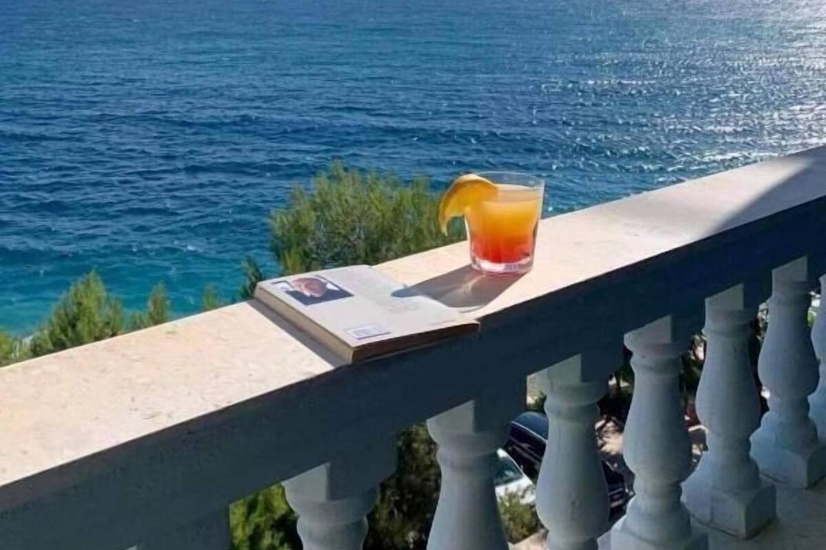 A balcony with a clear view of the sea and distant mountains.