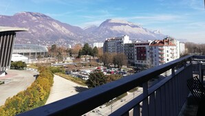 Stadtansicht mit modernen Gebäuden, einem Parkplatz und Bergen im Hintergrund.