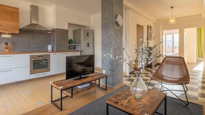 Eine moderne Küche mit Einbauofen, großem Fernseher und einem Holzesstisch mit Blumenvase.