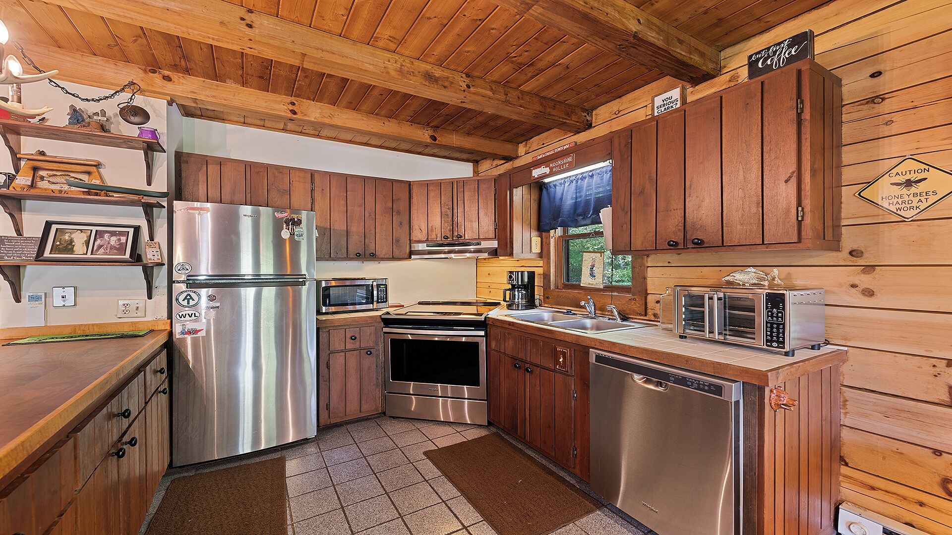 A compact kitchen with wooden cabinets, stainless steel appliances, and a coffee station.