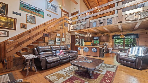 A spacious living room with a leather couch, a coffee table, and a staircase leading to an upper level. - 2BD 2BA Cozy Log Cabin, Easy Paved Access, View, Gas Log, Hot Tub, Wifi Pond (Waynesville)