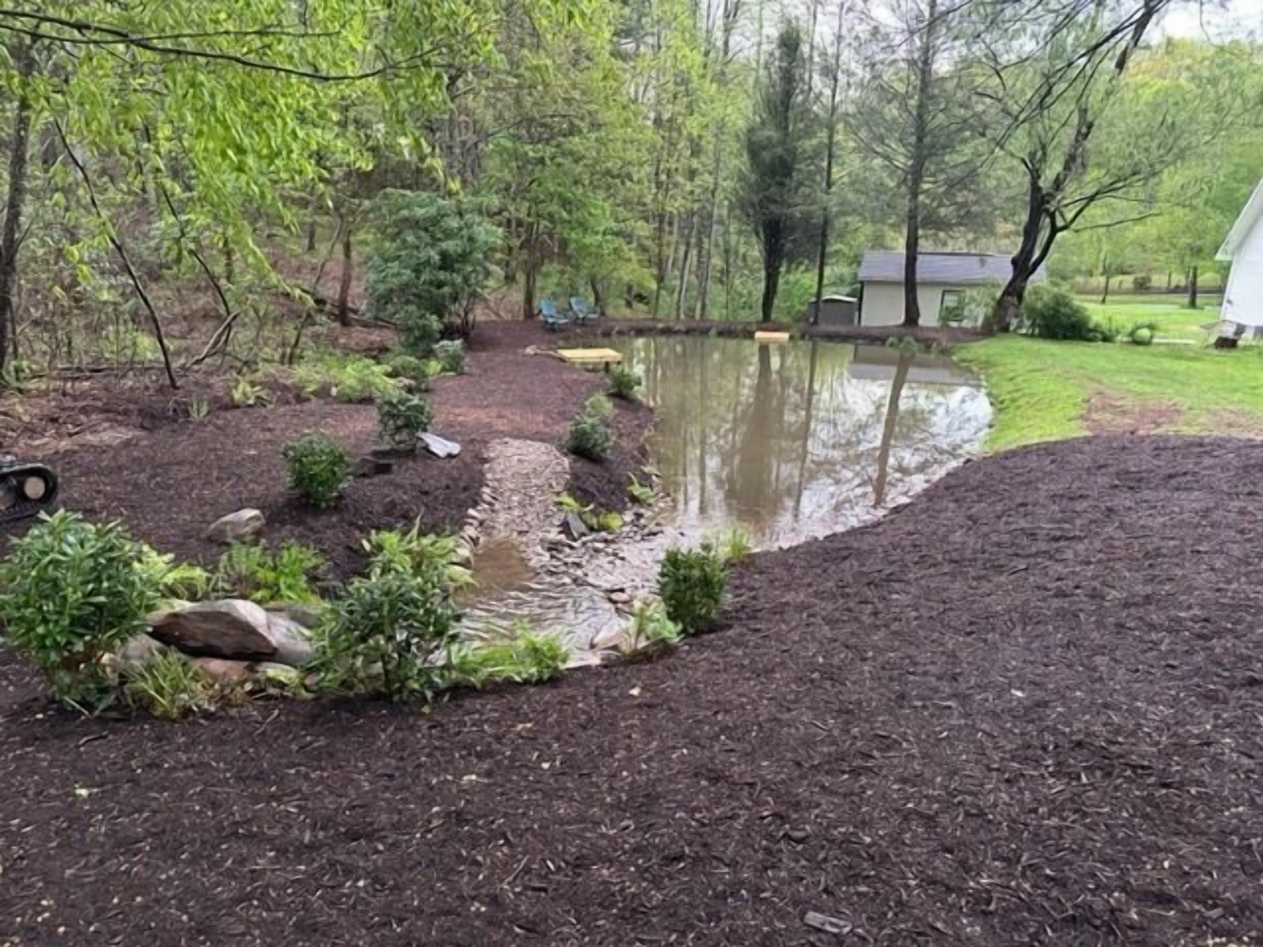 Un jardin avec un étang, entouré d’arbres et agrémenté d’un petit abri de jardin.