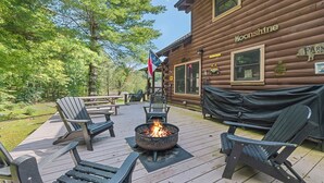 A wooden deck with Adirondack chairs, a fire pit, and a covered barbecue area at a cabin named 'Moonshine'. - 2BD 2BA Cozy Log Cabin, Easy Paved Access, View, Gas Log, Hot Tub, Wifi Pond (Waynesville)