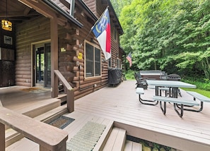 A wooden cabin with a deck, outdoor seating, and flags. - 2BD 2BA Cozy Log Cabin, Easy Paved Access, View, Gas Log, Hot Tub, Wifi Pond (Waynesville)