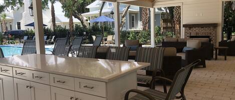 An outdoor patio area with a pool, lounge chairs, and a fireplace.