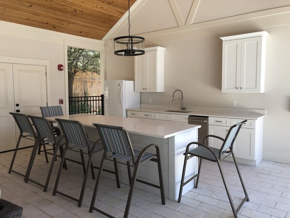 A modern kitchen with a central island, white cabinetry, and a dining area with striped chairs. - Latitude Adjustment @ Ocean Oaks 3 bedrooms, 2.5 bathrooms (Jekyll Island)