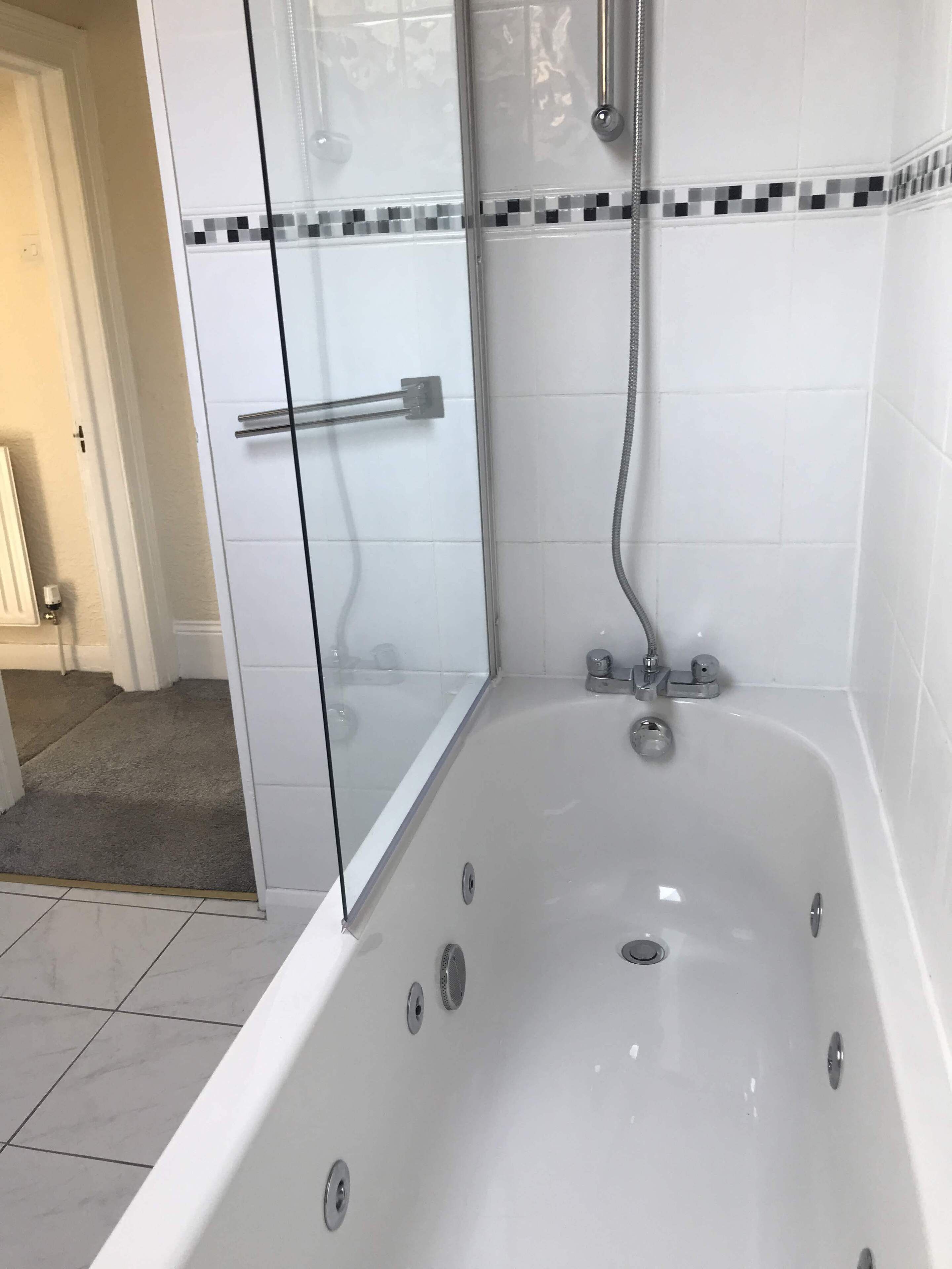 Un baño con cabina de ducha de vidrio, una bañera blanca y piso de baldosas.