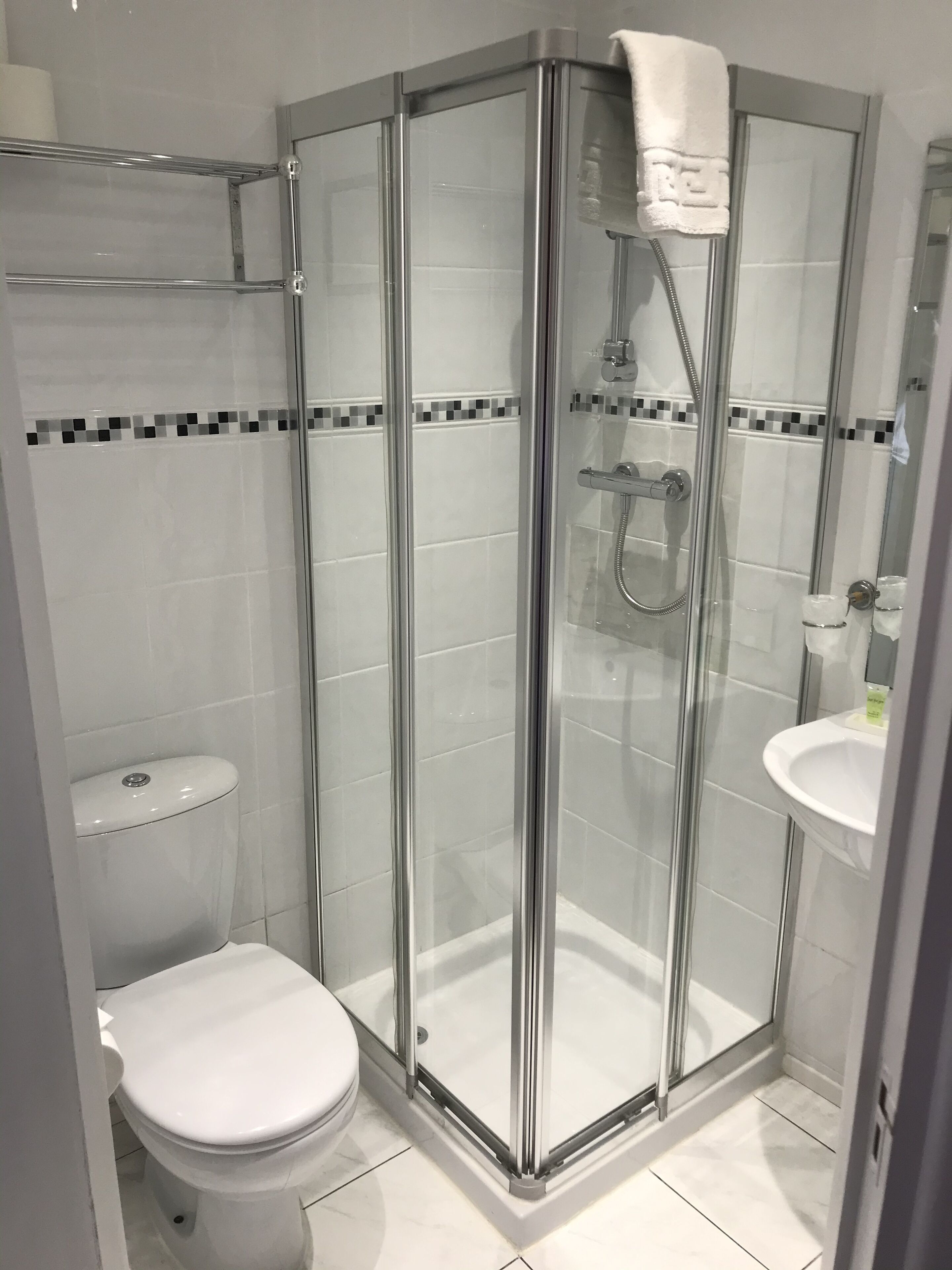 Un baño moderno con ducha de vidrio, inodoro blanco y lavamanos con espejo.