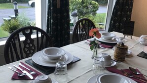 A table set for dining with white plates, bowls, and a vase with a single flower. - Princetown Guesthouse (Bangor)