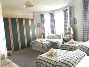 A hotel room with two beds, a wardrobe, a desk, and a window with curtains. - Princetown Guesthouse (Bangor)