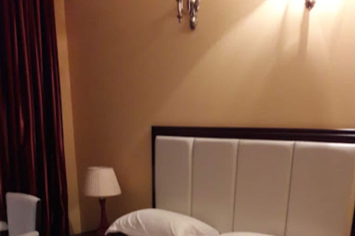 A hotel room with a bed, a nightstand, a lamp, and a chair.
