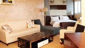 Una habitación de hotel con sofá, cama, mesita de noche y lámpara.