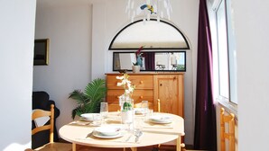 A dining area with a round table set for four, a wooden cabinet with a mirror above, and a window with purple curtains. - AP197 - Capuchinos - Beautiful apartment with Jacuzzi and free Wi-Fi (Nerja)