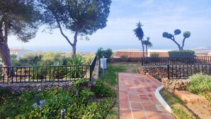 A garden pathway leading to a scenic overlook with a view of the sea and distant buildings. - AP197 - Capuchinos - Beautiful apartment with Jacuzzi and free Wi-Fi (Nerja)