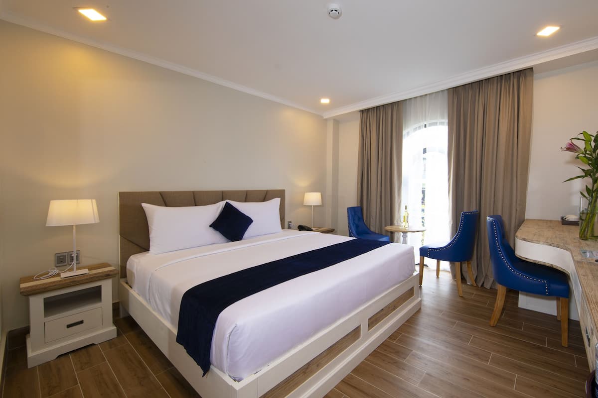 Une chambre d’hôtel comprenant un lit, des tables de chevet, un bureau, des chaises et une vue sur l’extérieur.