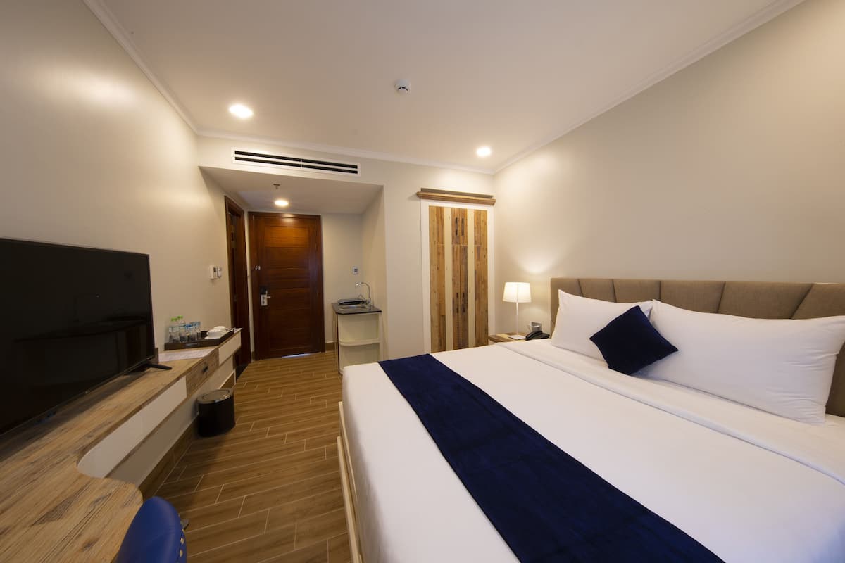 Une chambre d’hôtel avec un grand lit, une télévision, un bureau et une armoire.