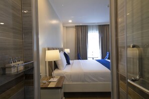 Relax in a serene space with a large bed, glass shower, and natural light pouring in through the large window.