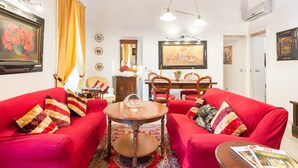 A living room with red sofas, a wooden coffee table, and a dining area with a wooden table and chairs.