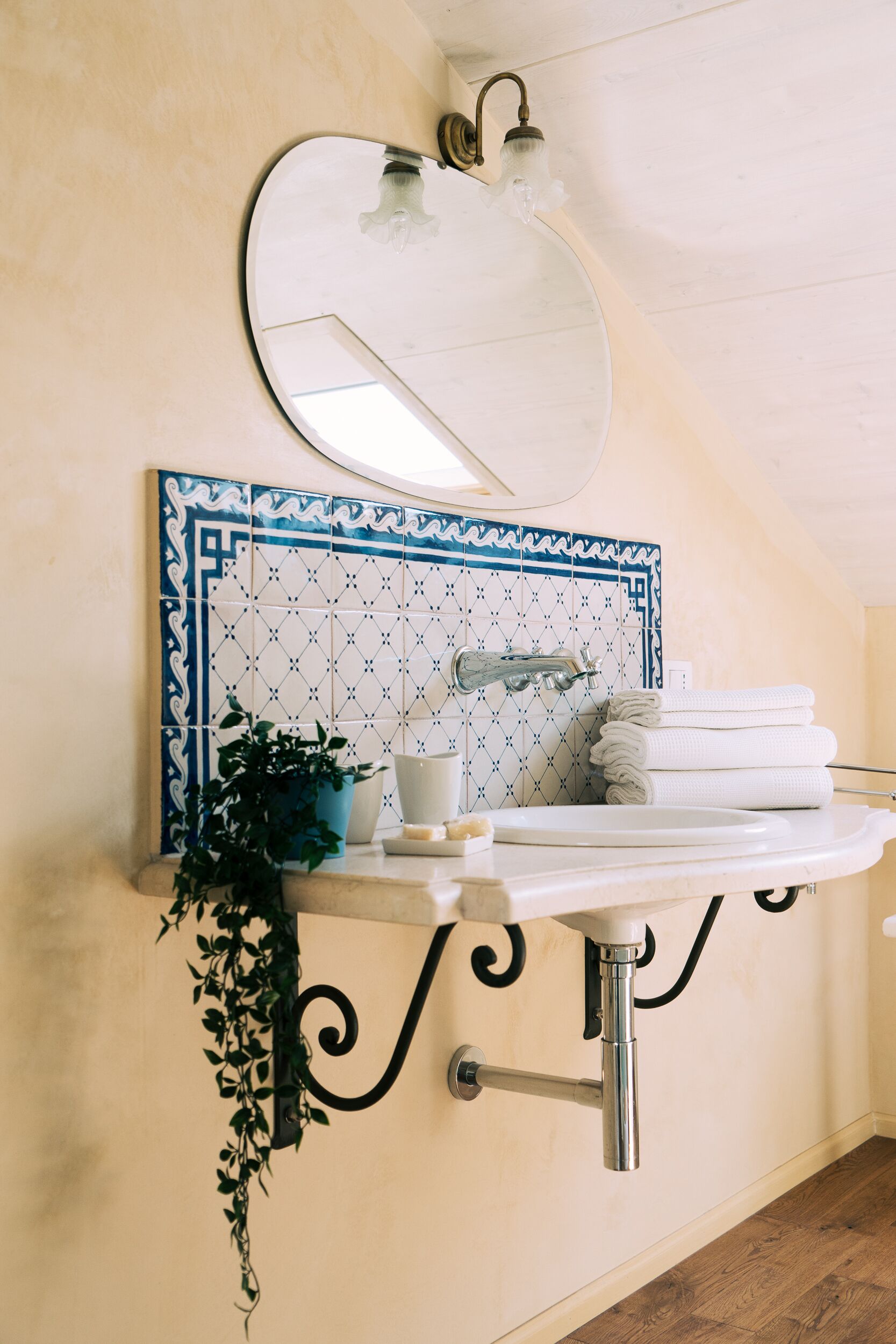 Une salle de bain avec un lavabo blanc, un miroir et un mur recouvert de carreaux bleus à motifs.