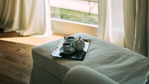 A room with a bed, a tray with a teapot and cups, and a view of a green landscape through a window with white curtains. - Charm and hospitality at 500 meters from the sea. Pool surrounded by greenery (Civitanova marche)