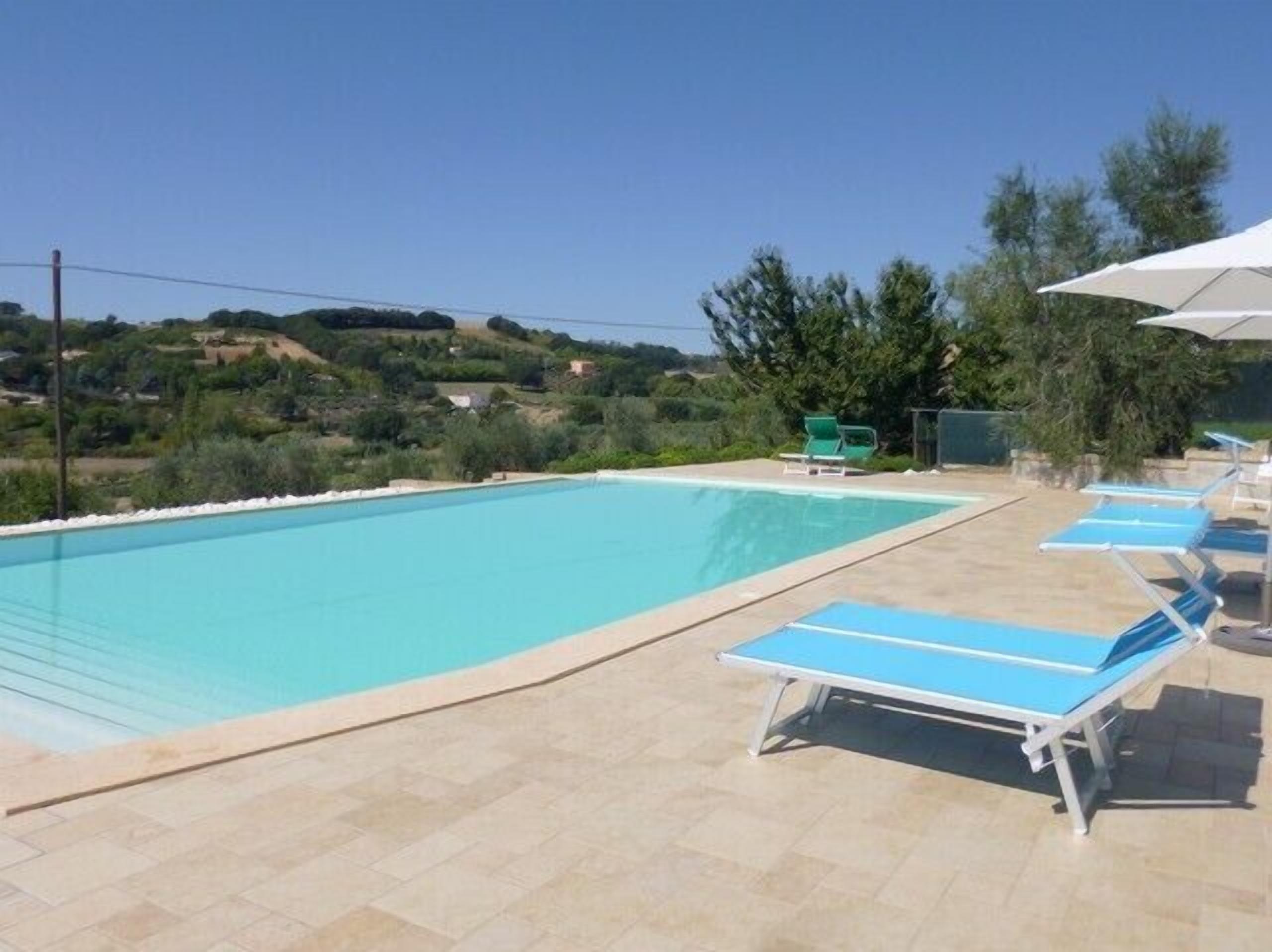 Een buitenzwembad, ligstoelen bij het zwembad