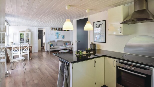Une cuisine moderne dotée d’un îlot central, d’appareils électroménagers en acier inoxydable et de luminaires suspendus.